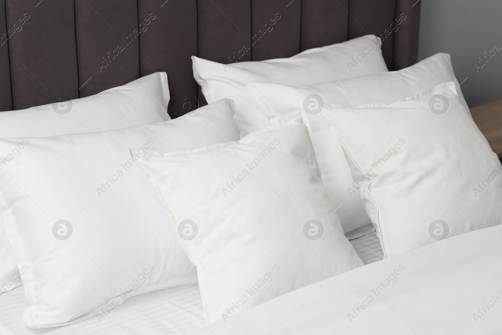 Photo of Many soft pillows on bed at home, closeup