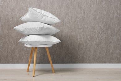 Photo of Many soft pillows on chair near grey wall. Space for text