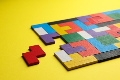 Photo of Colorful wooden puzzle pieces on yellow background, closeup