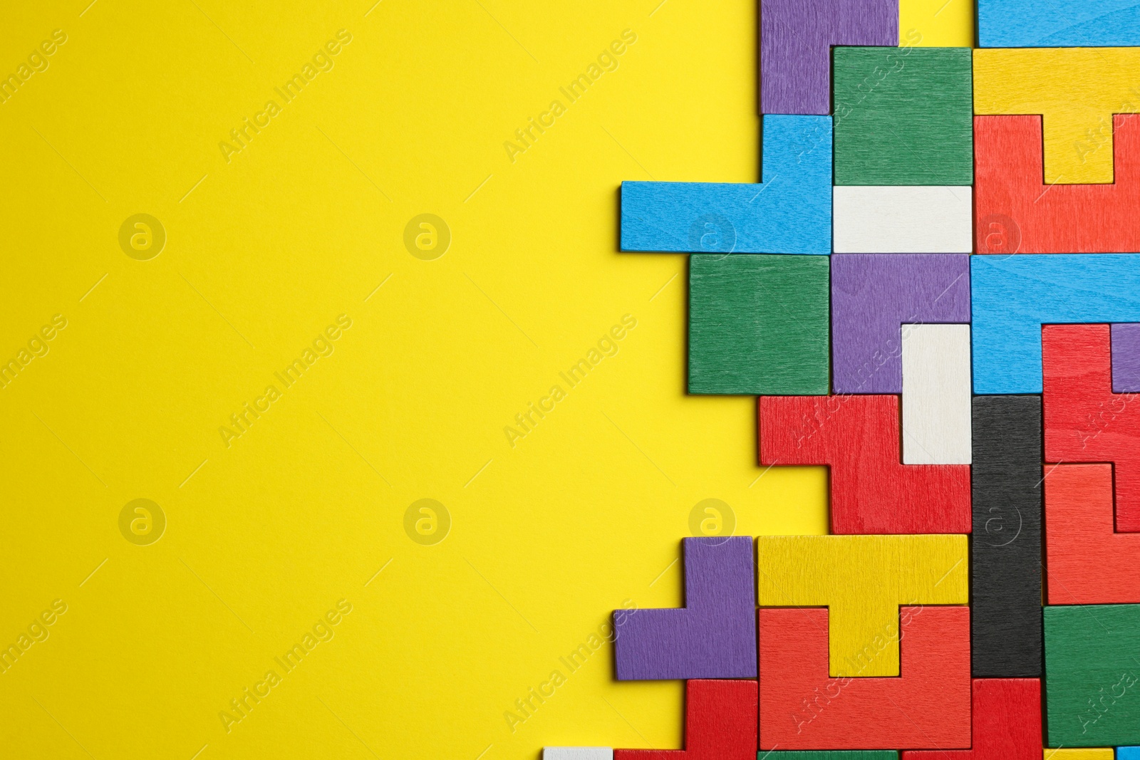 Photo of Colorful wooden puzzle pieces on yellow background, top view