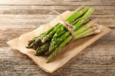 Bunch of fresh green asparagus stems on wooden table, closeup