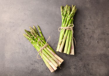 Bunches of fresh green asparagus stems on grey textured table, flat lay