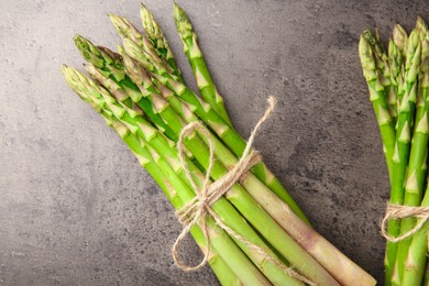 Photo of Fresh green asparagus stems on grey textured table, flat lay