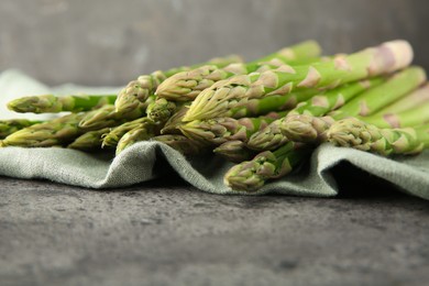 Fresh green asparagus stems on grey textured table, closeup