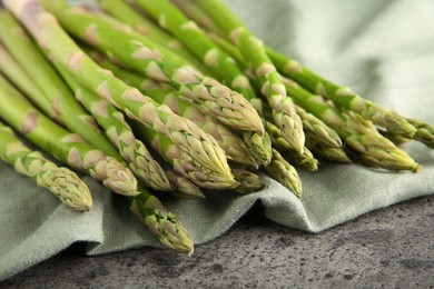 Photo of Fresh green asparagus stems on grey textured table, closeup