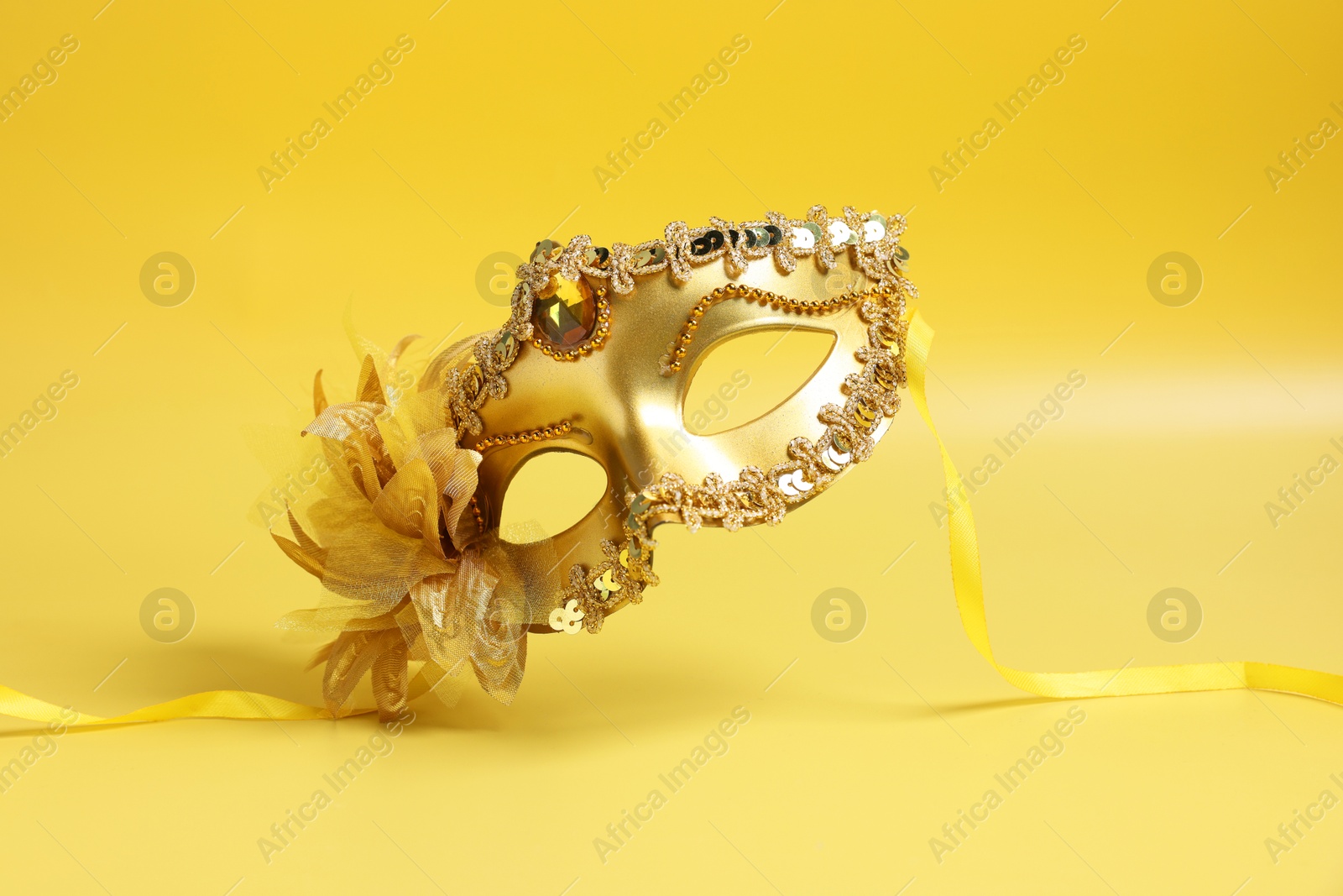 Photo of Beautiful carnival mask in air on yellow background