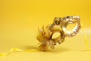 Photo of Beautiful carnival mask in air on yellow background