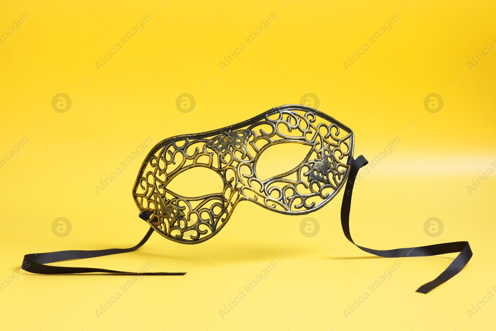 Photo of Beautiful carnival mask in air on yellow background