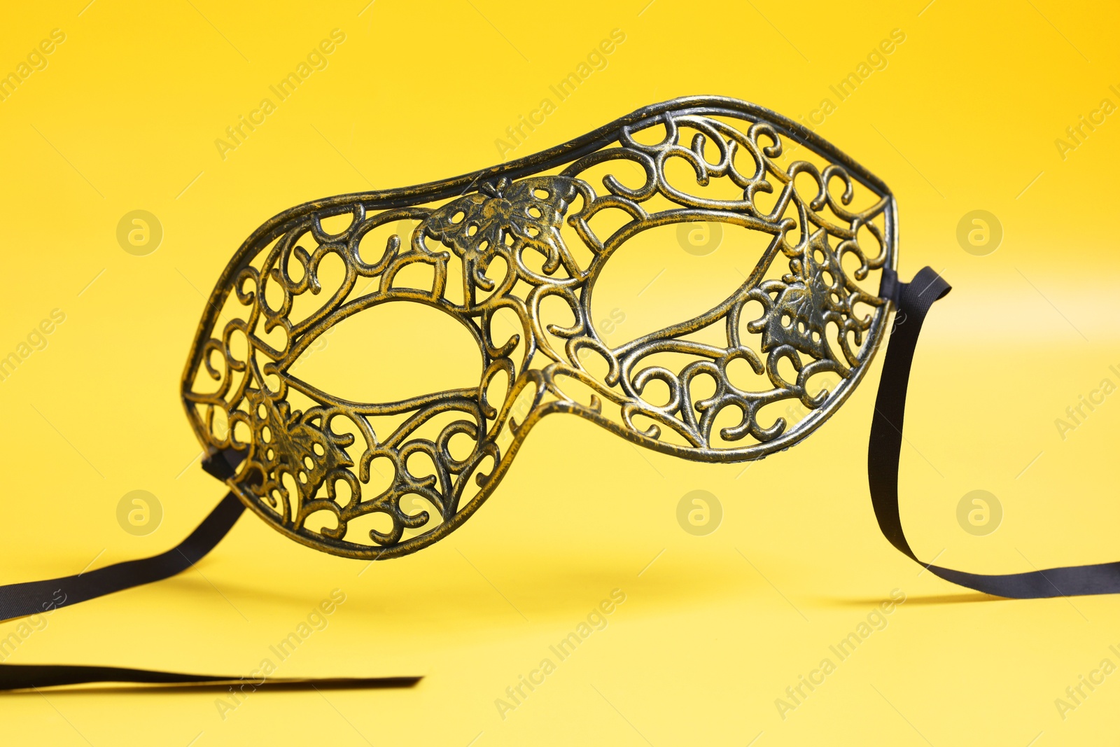 Photo of Beautiful carnival mask in air on yellow background