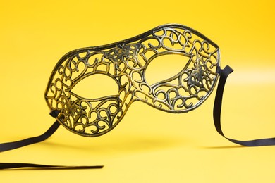 Photo of Beautiful carnival mask in air on yellow background