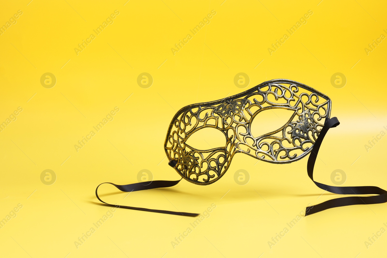 Photo of Beautiful carnival mask in air on yellow background