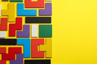 Photo of Colorful wooden puzzle pieces on yellow background, top view