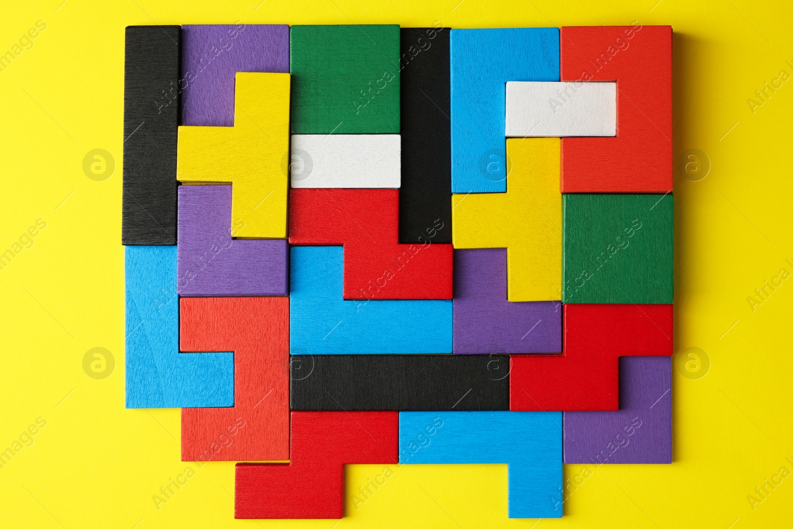 Photo of Colorful wooden puzzle pieces on yellow background, top view