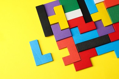 Photo of Colorful wooden puzzle pieces on yellow background, top view