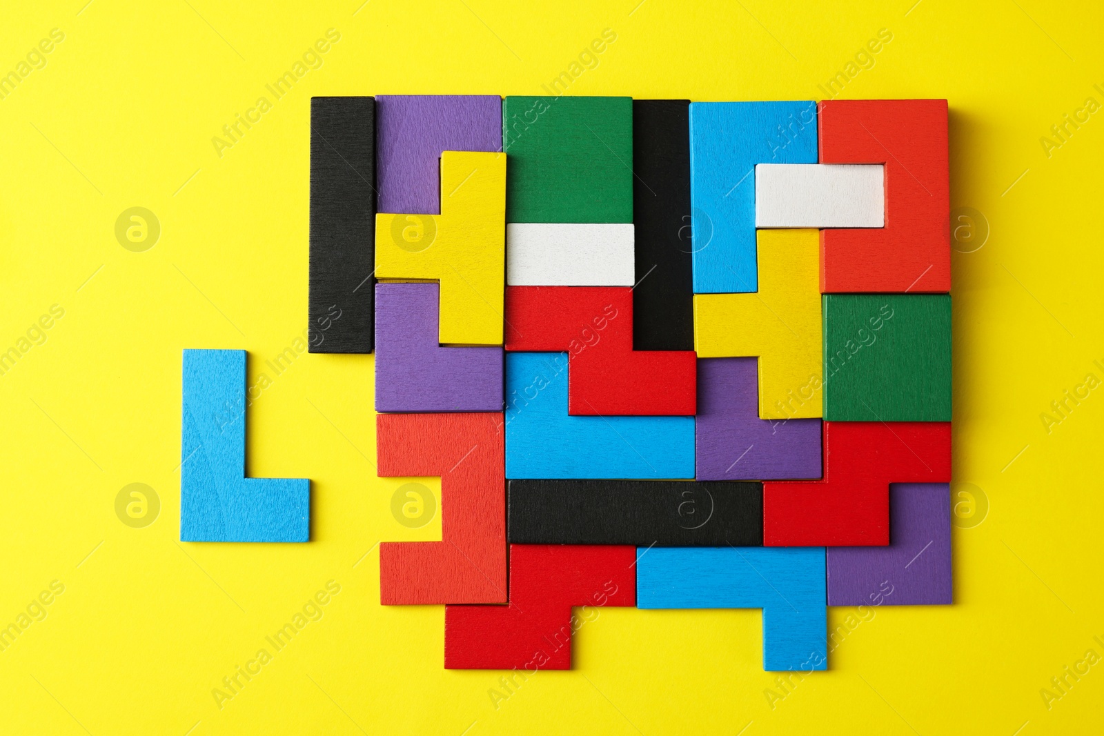 Photo of Colorful wooden puzzle pieces on yellow background, top view