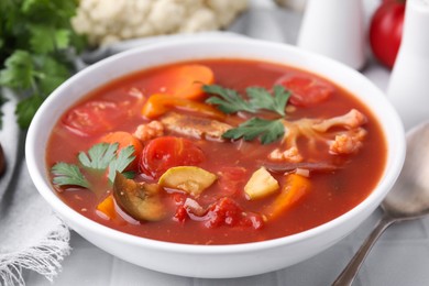 Delicious homemade stew in bowl on white tiled table, closeup