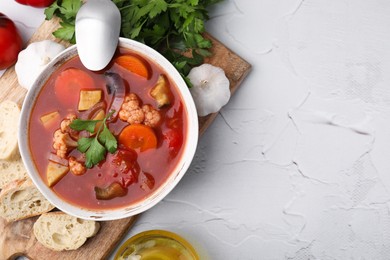 Photo of Delicious homemade stew in bowl, bread and parsley on light table, flat lay. Space for text