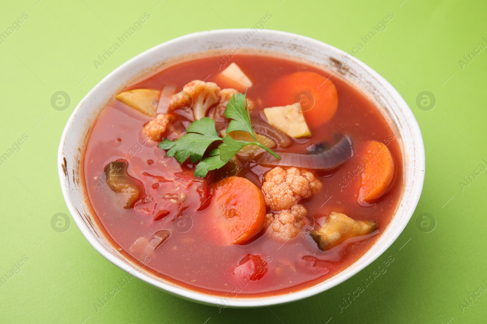 Photo of Delicious homemade stew in bowl on green background, closeup