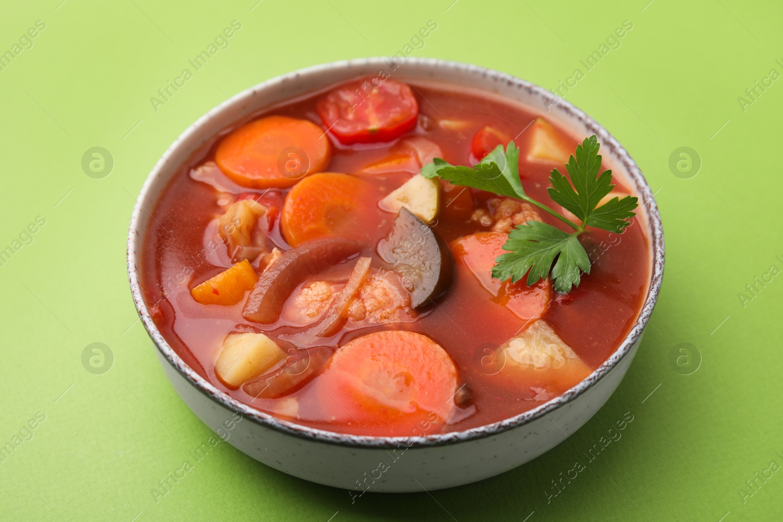 Photo of Delicious homemade stew in bowl on green background, closeup