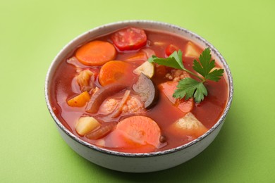 Delicious homemade stew in bowl on green background, closeup