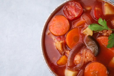 Photo of Delicious homemade stew in bowl on light table, top view. Space for text