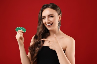 Smiling woman pointing at poker chips on red background