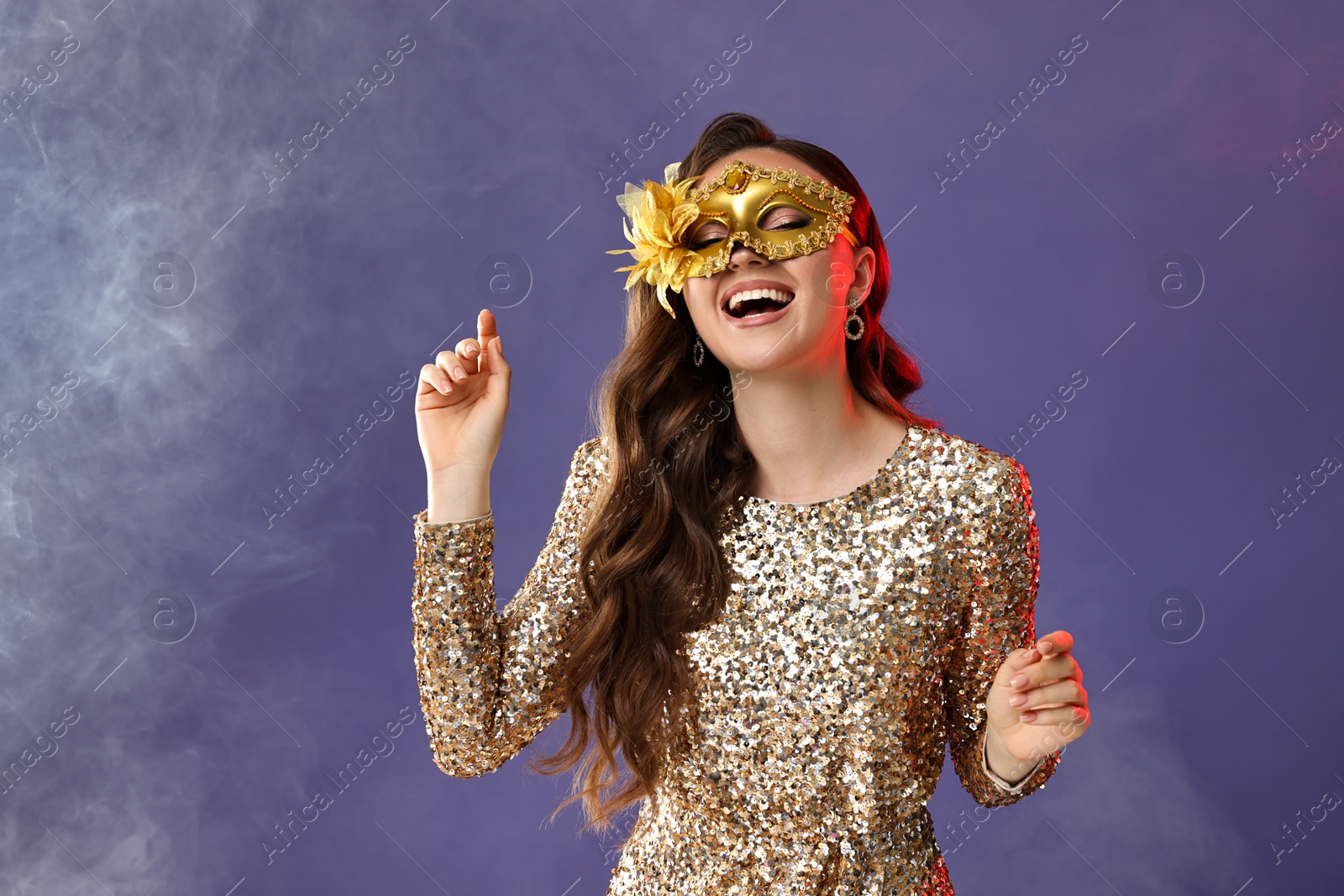 Photo of Happy woman wearing carnival mask on purple background with smoke