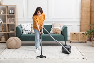 Young woman cleaning carpet with vacuum in living room