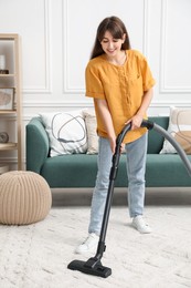 Young woman cleaning carpet with vacuum in living room