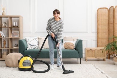 Young woman cleaning carpet with vacuum in living room