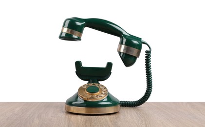 Photo of Green vintage corded telephone on wooden table against light background