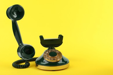 Photo of Green vintage corded telephone on yellow background, space for text