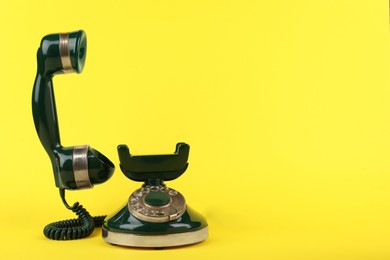 Photo of Green vintage corded telephone on yellow background, space for text