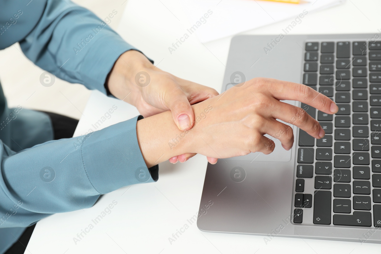 Photo of Carpal tunnel syndrome. Woman suffering from pain in wrist at desk, closeup