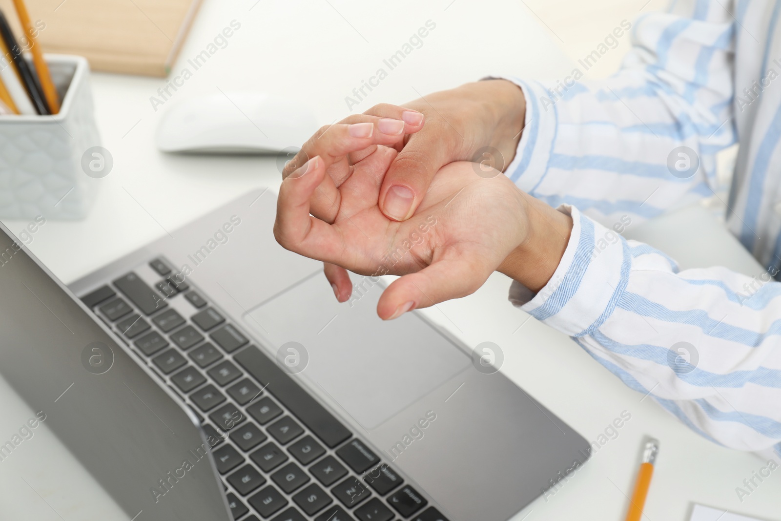 Photo of Carpal tunnel syndrome. Woman suffering from pain in wrist at desk, closeup