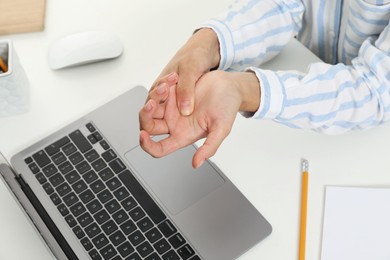 Photo of Carpal tunnel syndrome. Woman suffering from pain in wrist at desk, closeup