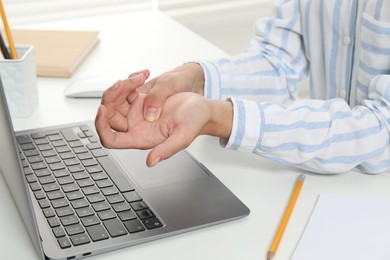 Photo of Carpal tunnel syndrome. Woman suffering from pain in wrist at desk, closeup