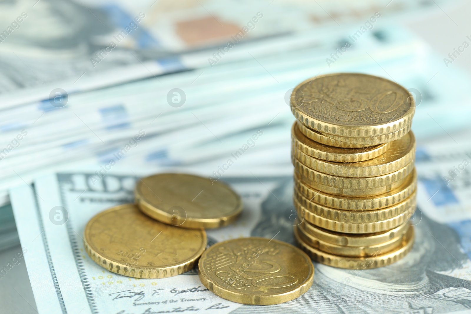 Photo of Stacked euro coins on dollar banknotes, closeup