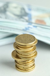 Photo of Stack of euro coins and dollar banknotes on white table, closeup