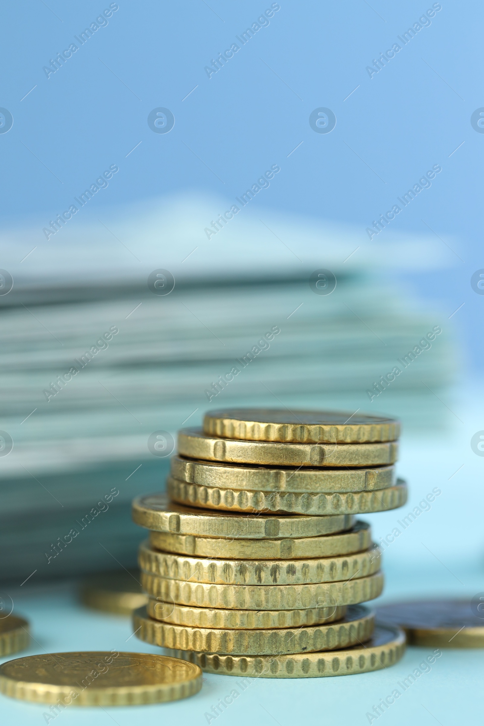 Photo of Stack of euro coins on light blue background, closeup