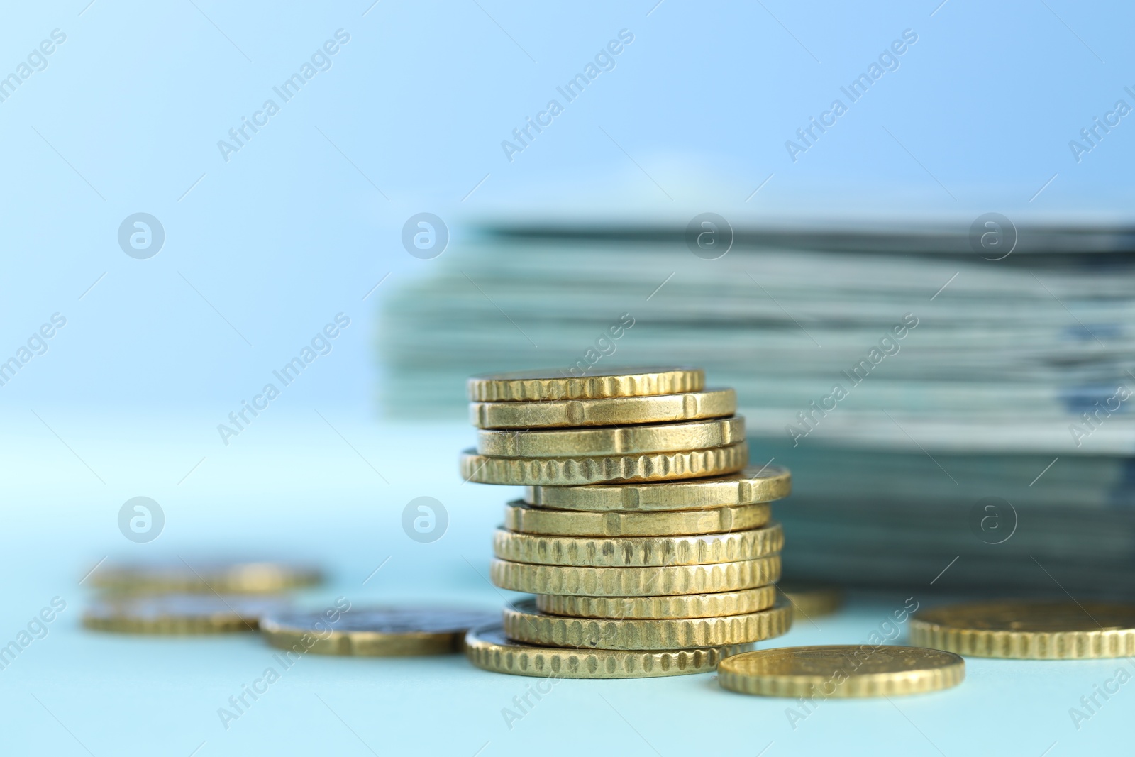 Photo of Stack of euro coins on light blue background, closeup