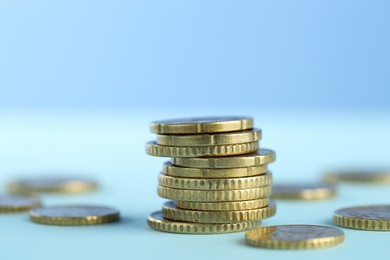 Photo of Stack of euro coins on light blue background, closeup