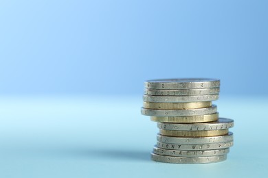 Photo of Stack of euro coins on light blue background, space for text