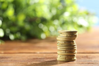 Photo of Stack of euro coins on wooden table, space for text