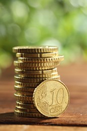 Photo of Stacked euro coins on wooden table, closeup