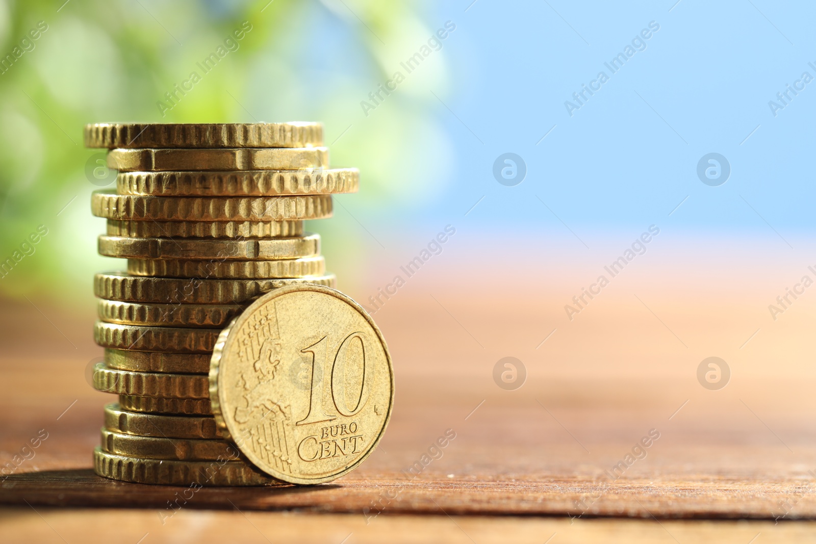 Photo of Stacked euro coins on wooden table, space for text