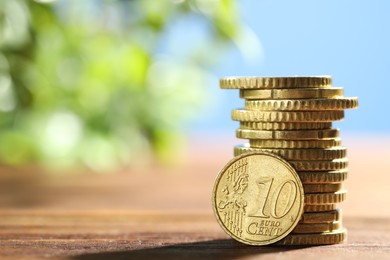 Photo of Stacked euro coins on wooden table, space for text