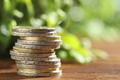 Photo of Stacked euro coins on wooden table, closeup. Space for text