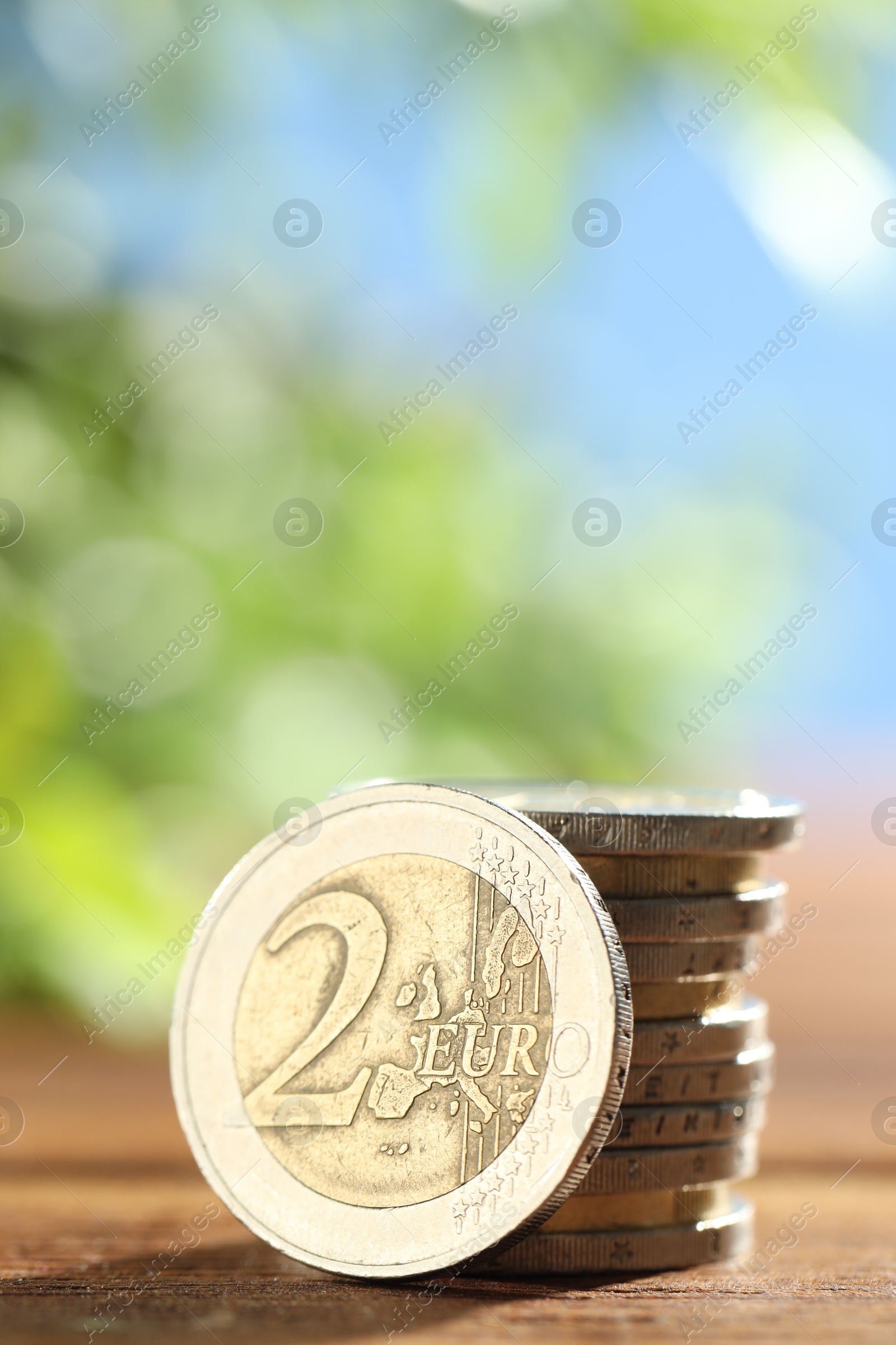 Photo of Stacked euro coins on wooden table, closeup