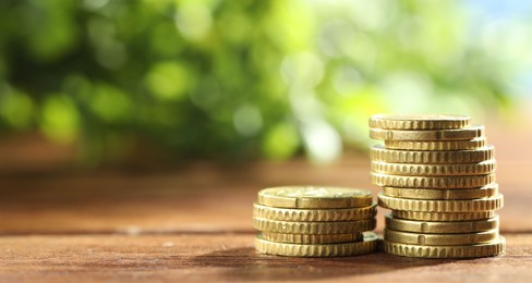 Photo of Stacked euro coins on wooden table, space for text